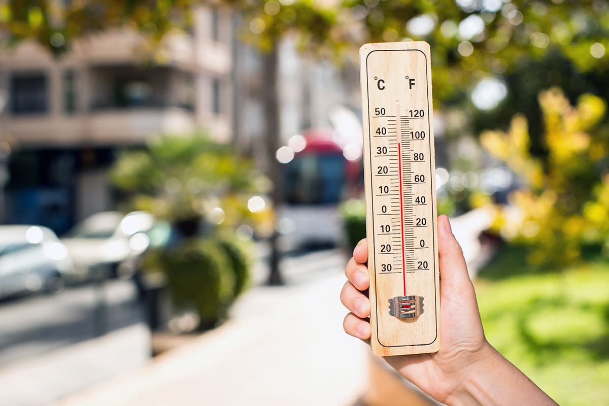 Hand holding a thermometer indicating hot temperatures