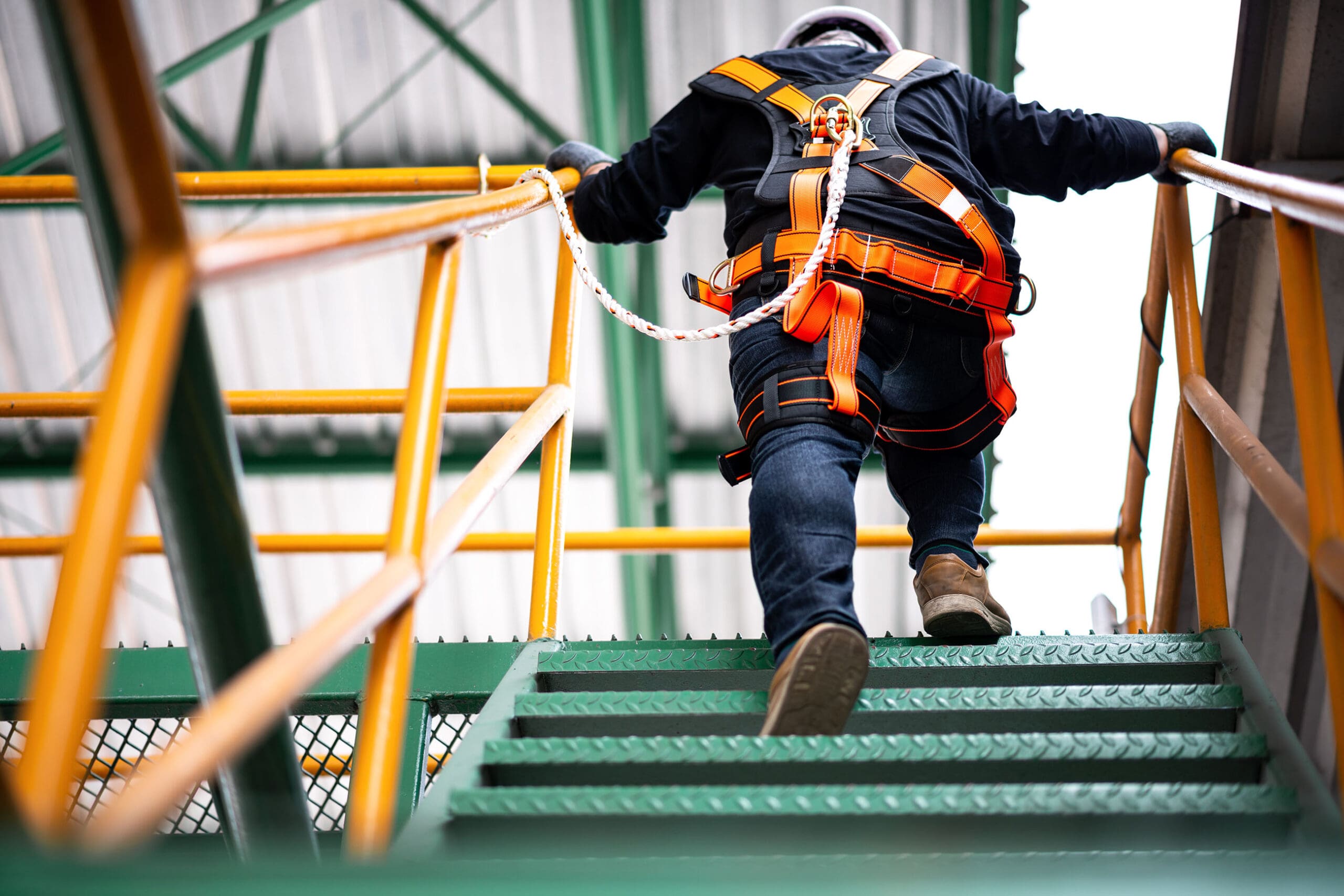 Man on jobsite walking up stairs with safety harness