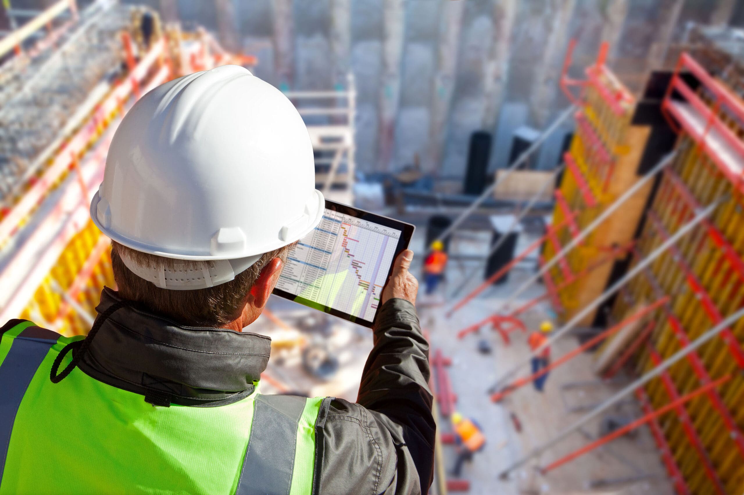 civil engineer or architect on construction site checking schedu Man looking at tablet on jobsite