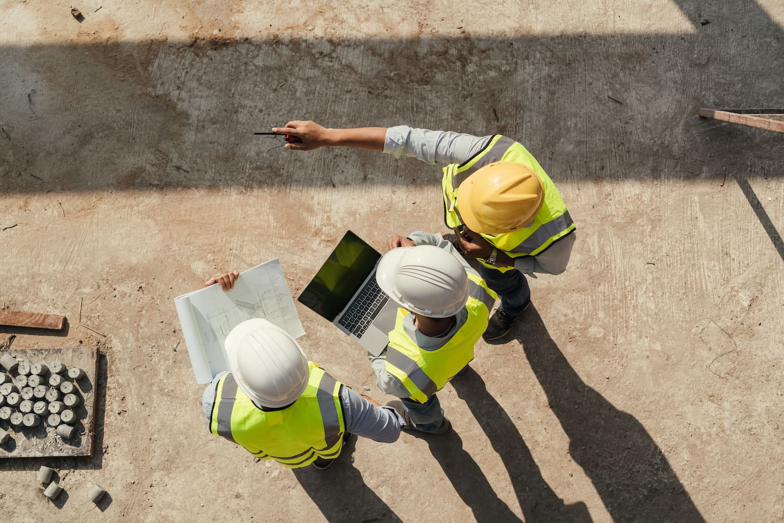 Men on jobsite wearing hardhats and looking at laptop